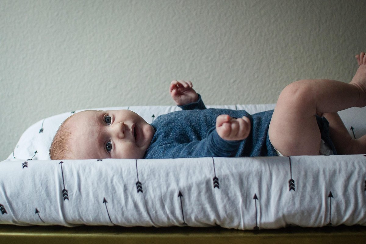 Bébé allongé sur un matelas à langer, en body, prêt pour le change
