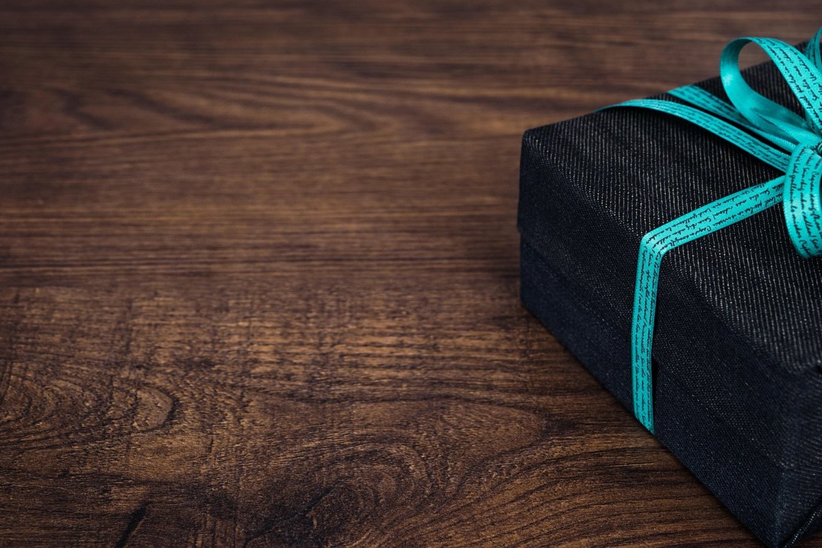 Cadeau emballé de papier sombre avec un ruban, posé sur du bois